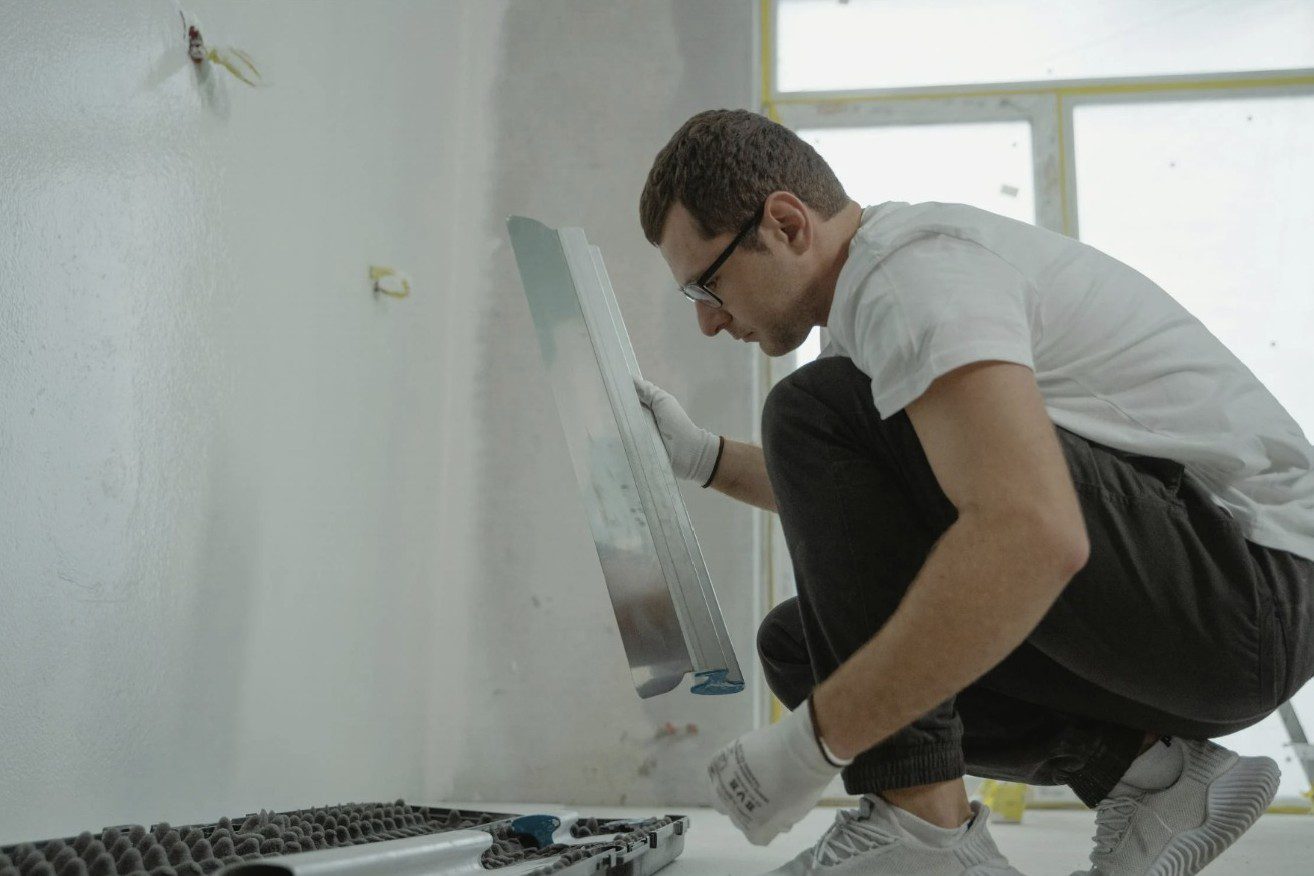 A man installing or repairing a radiator on a wall.